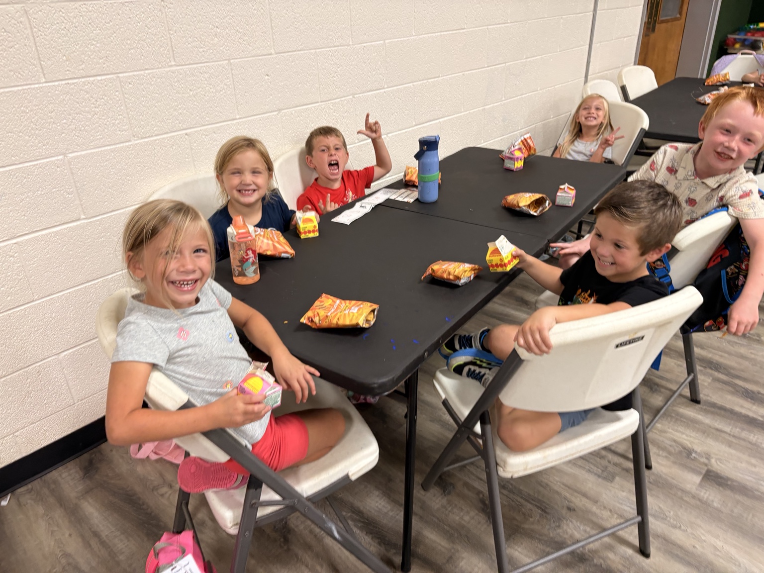 Children laughing and enjoying snacks together around a table