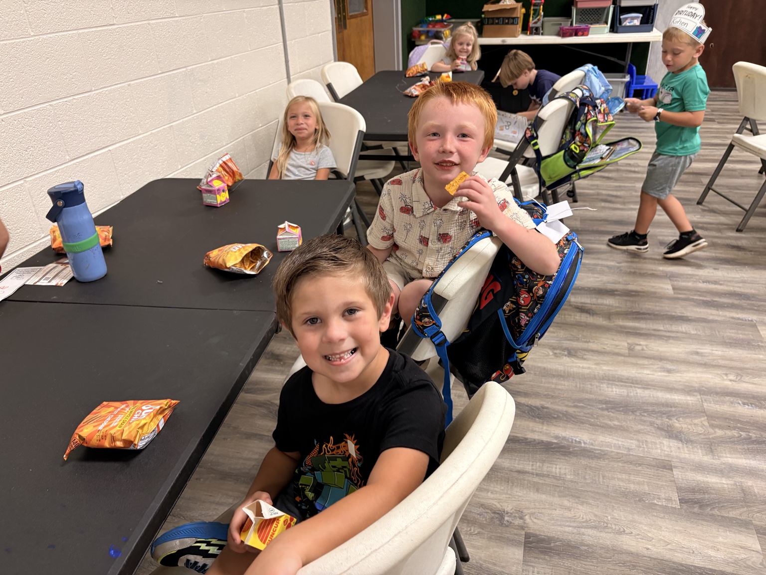 Children sharing snack time around tables at HomeBase96