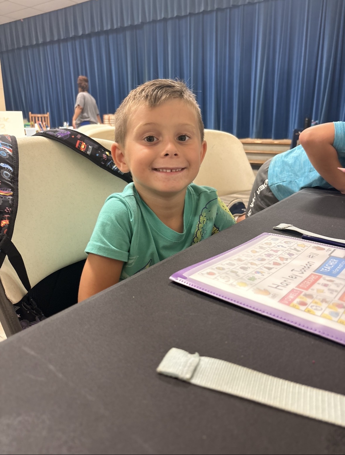 Child smiling while working on an activity at a table