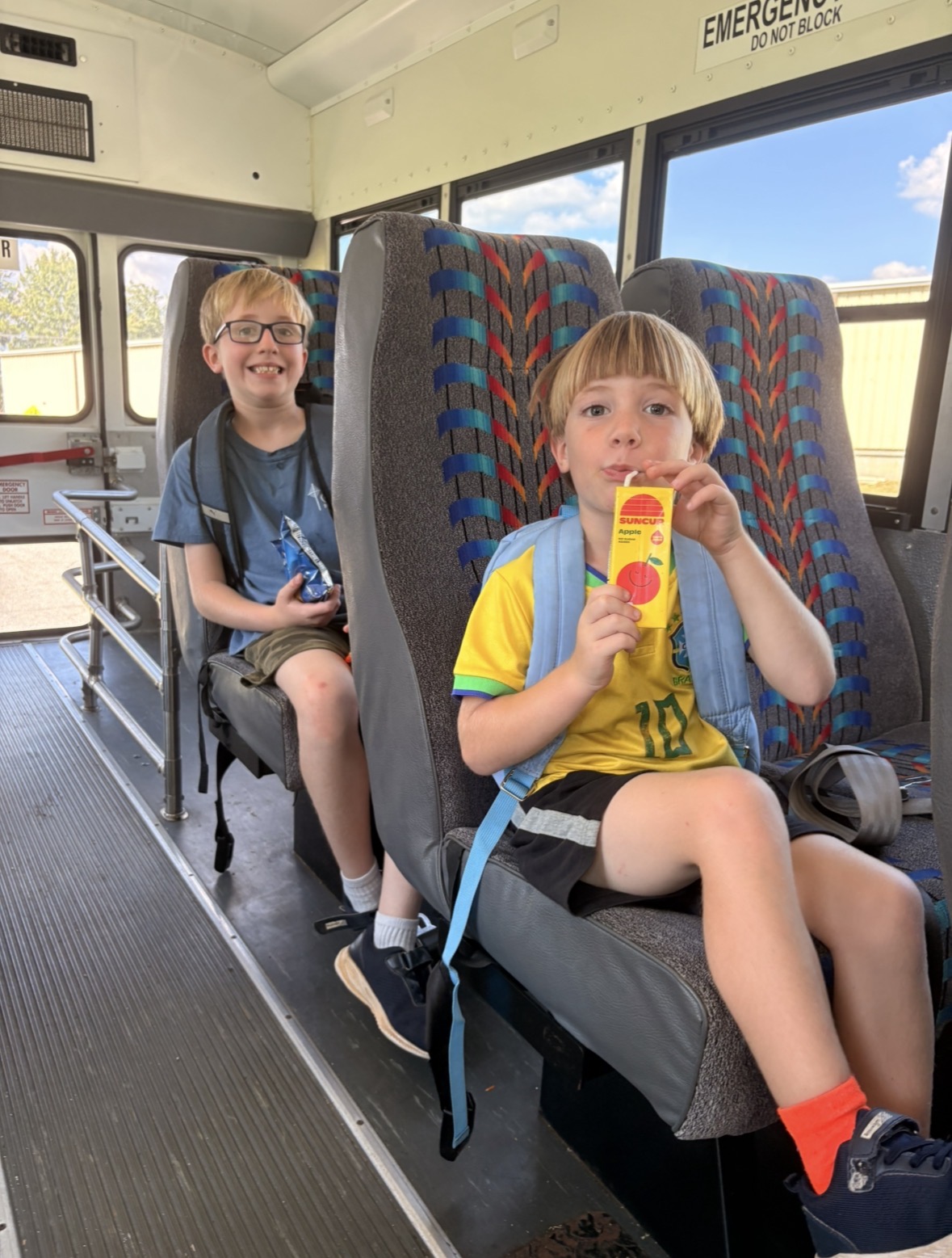 Two children enjoying a snack on the bus